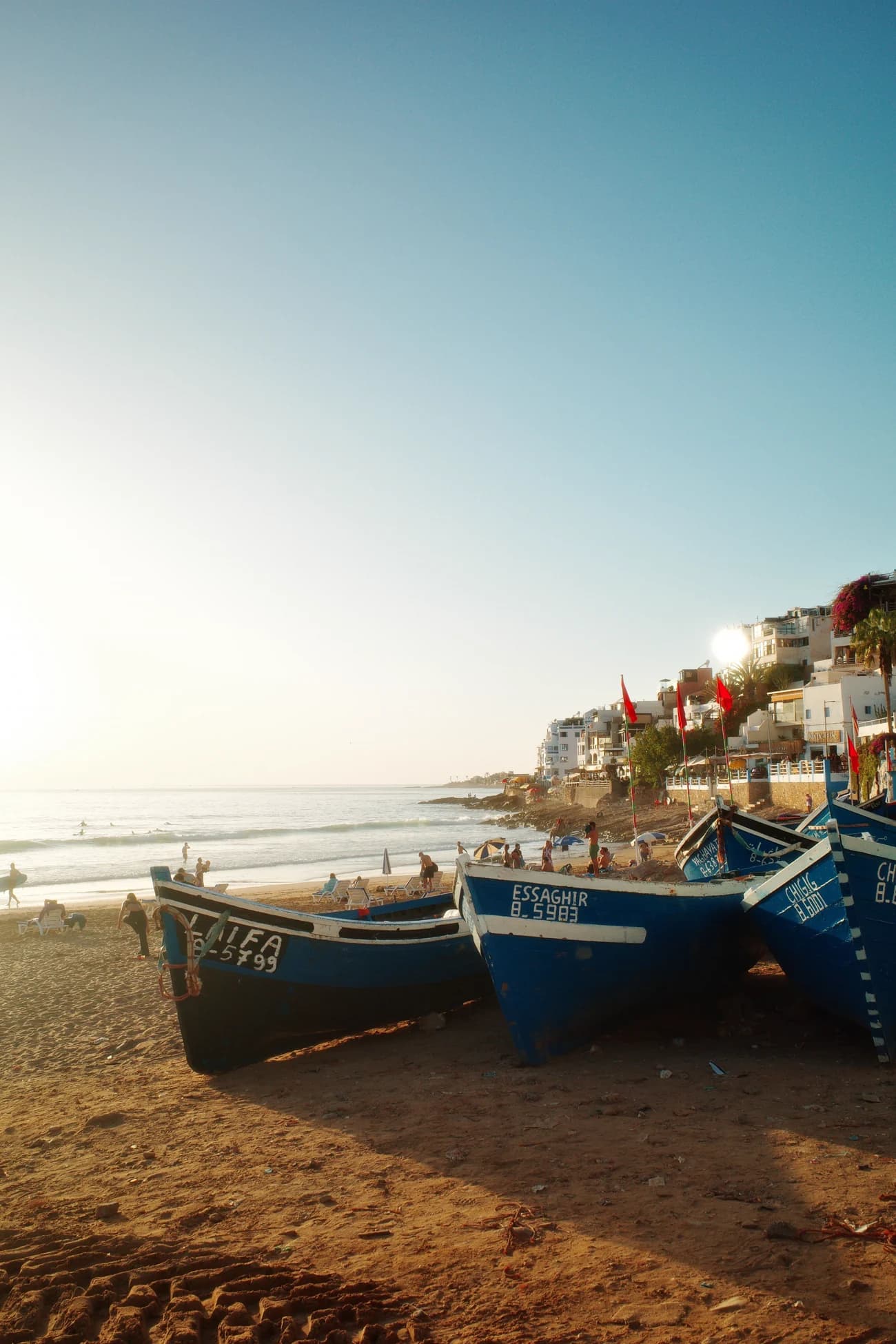 Blue fishing boats on the beach at Taghazout at golden hour.