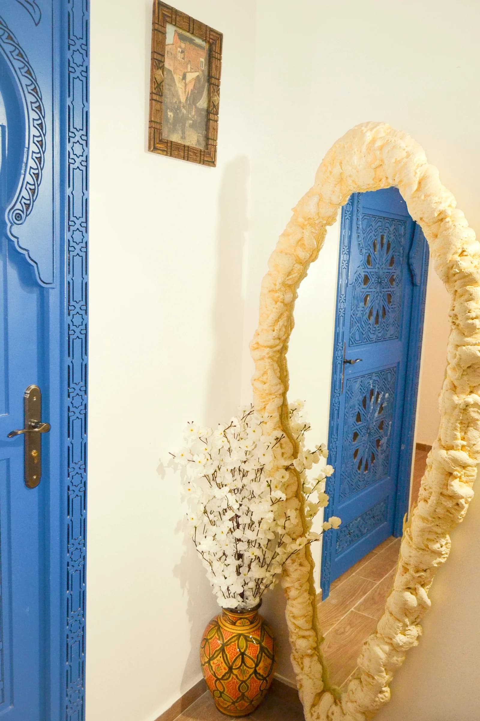 Blue-door hallway with a Moroccan mirror