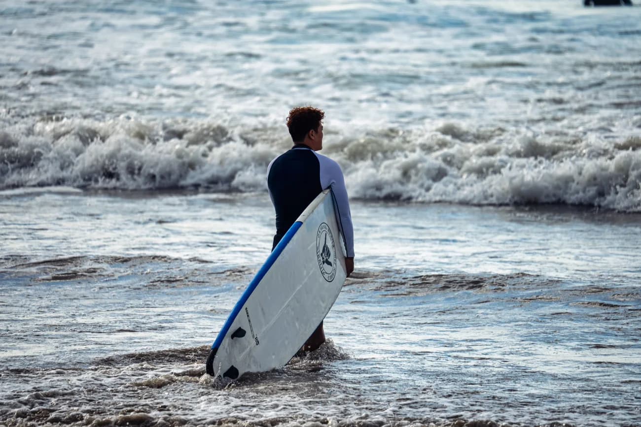 A lone surfer heading into the waves.