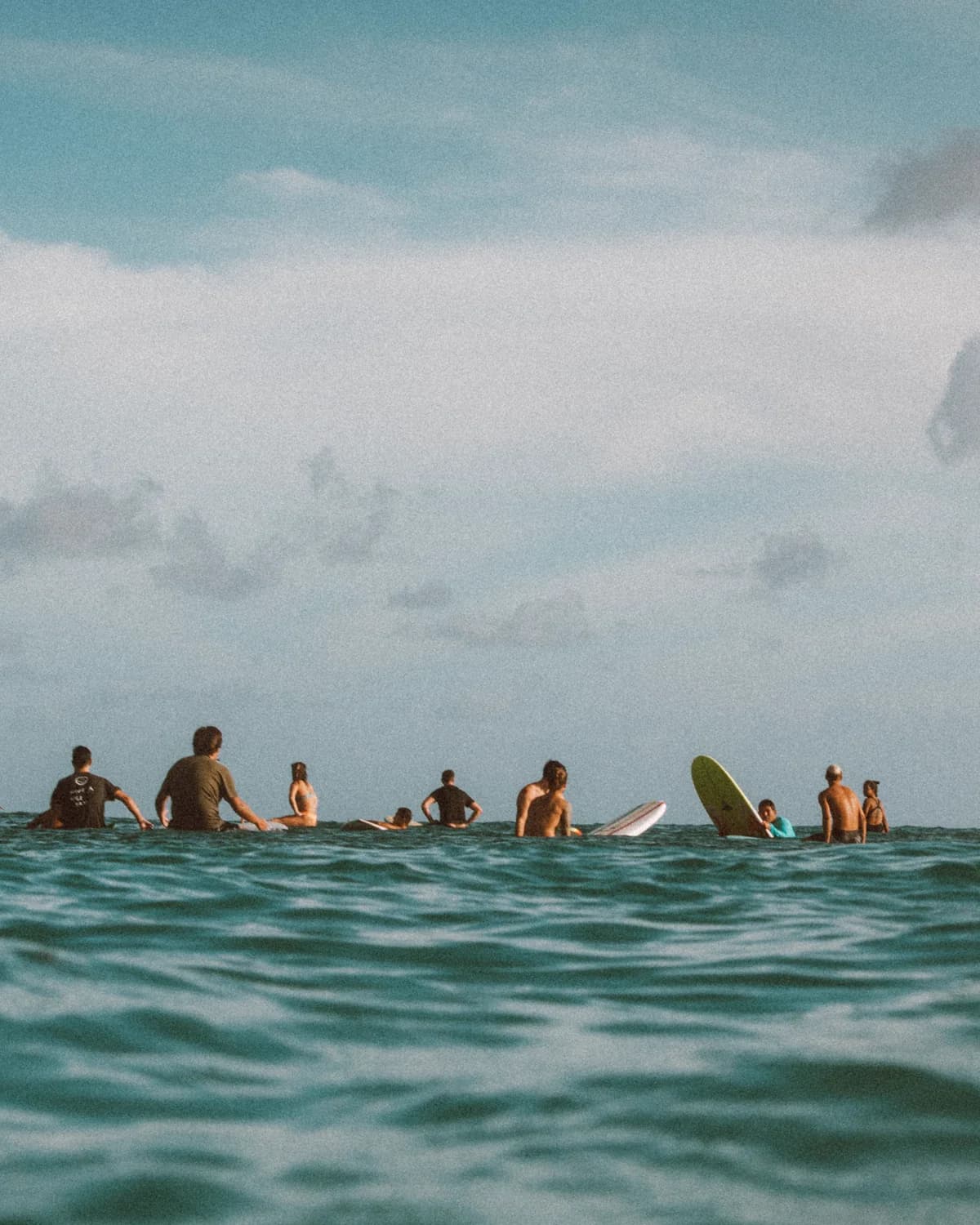 A group of surfers sitting together in the line-up, waiting for waves.