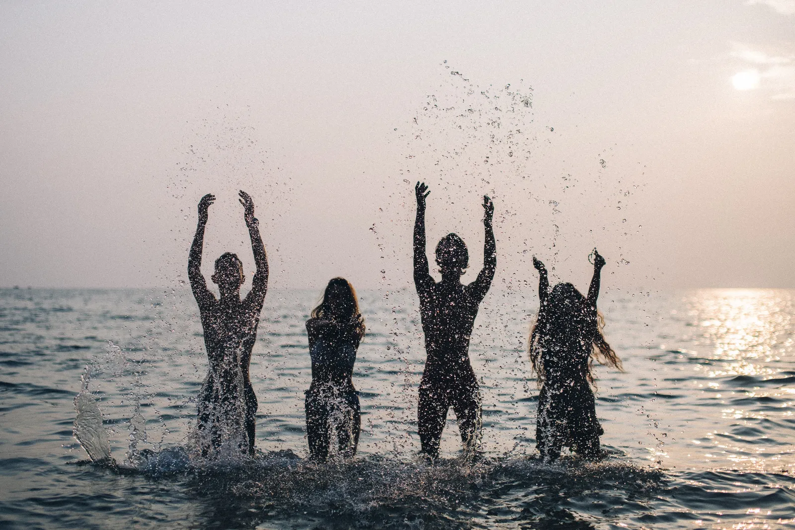 Four friends splashing in the Atlantic at dusk