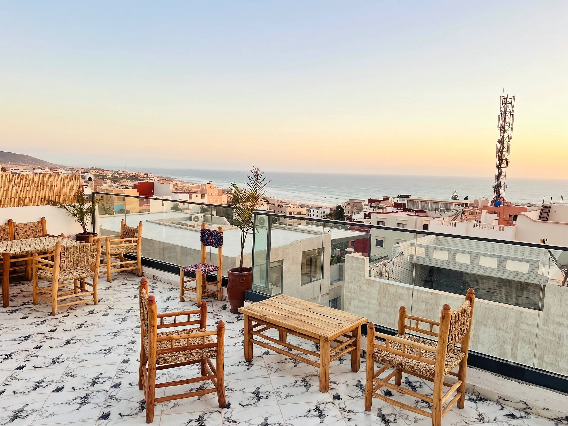 The White Pearl rooftop terrace at sunset, ocean beyond the village