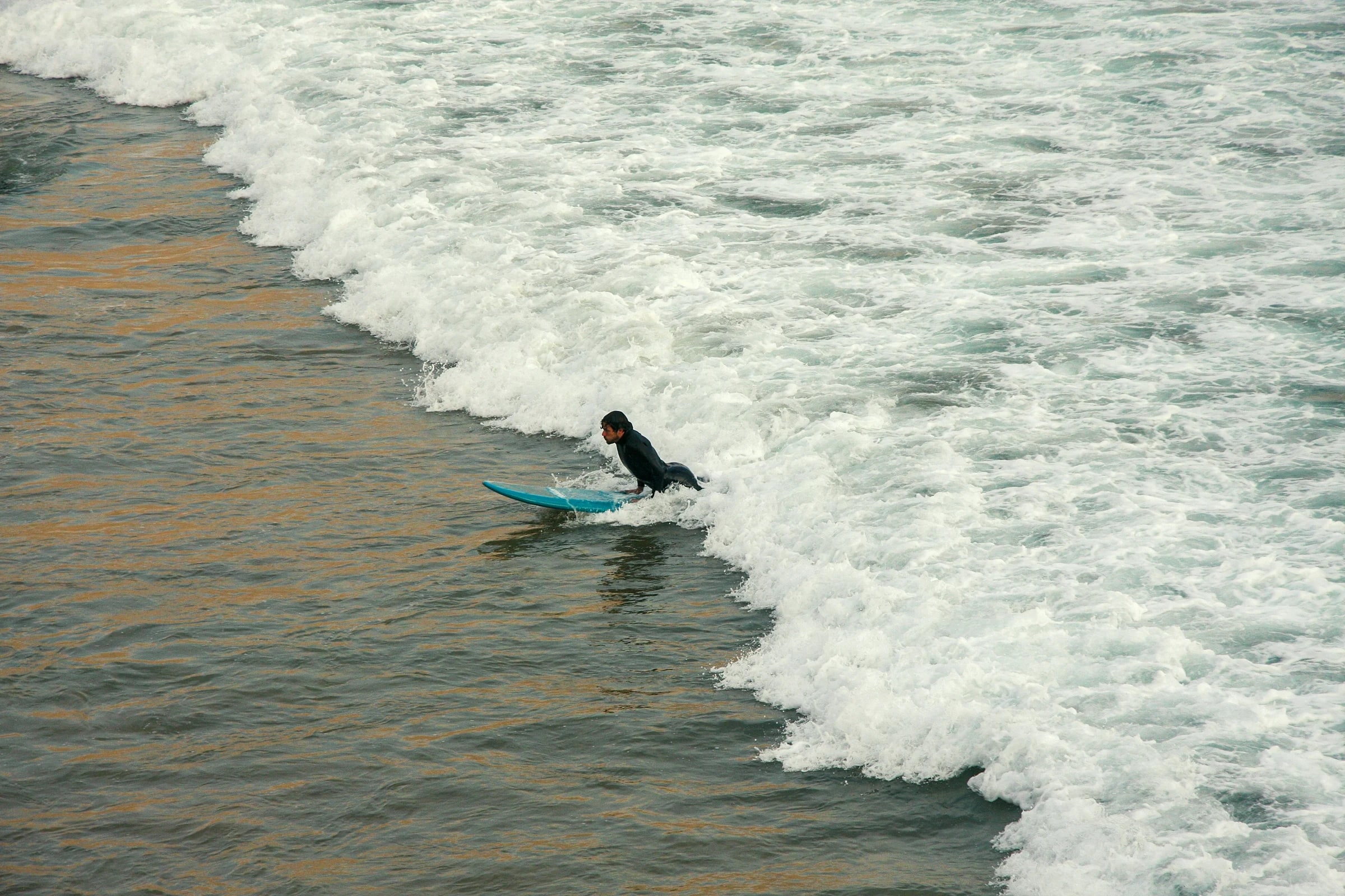 A surfer paddling out through the whitewater
