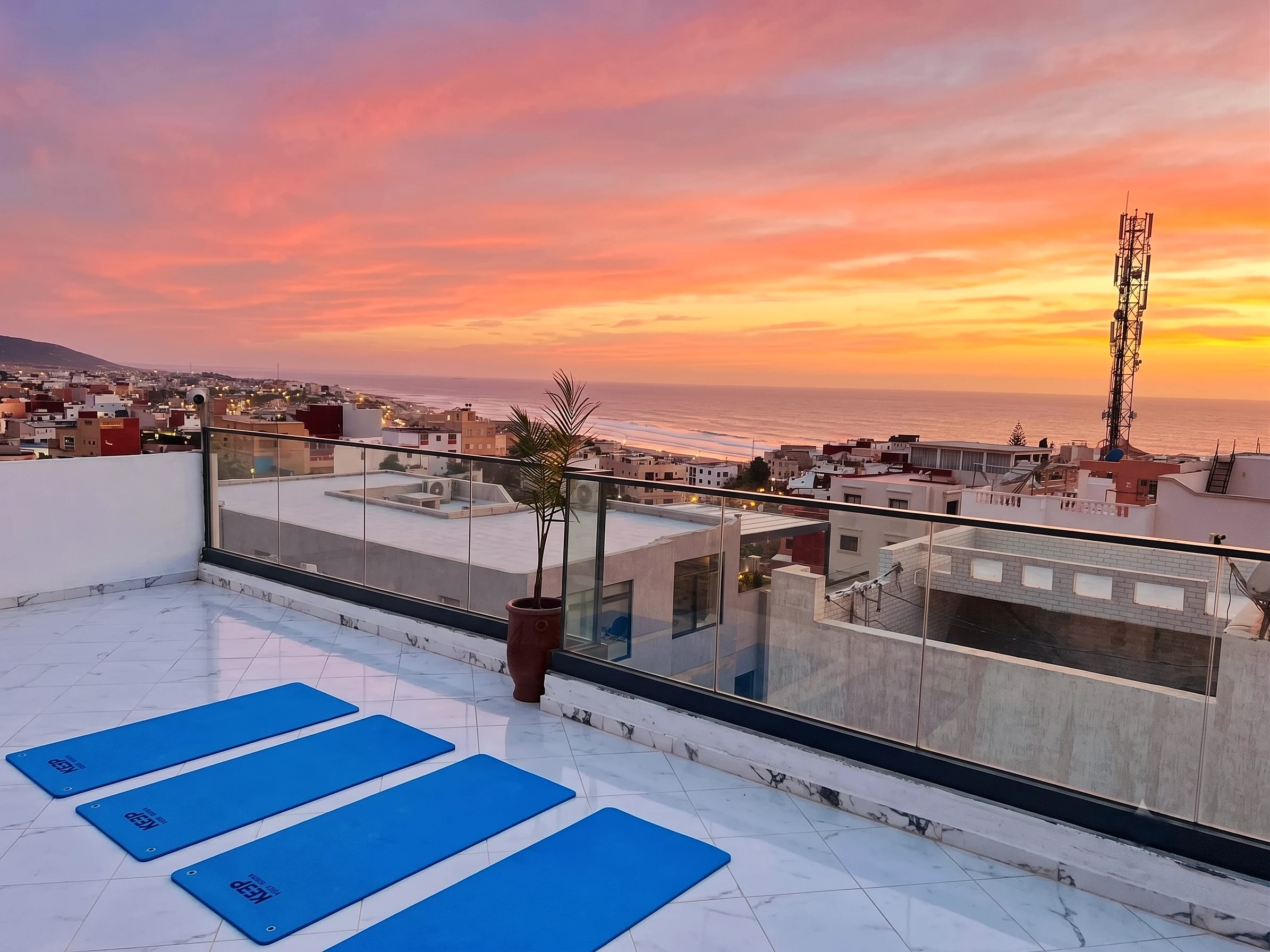 Yoga mats on the White Pearl rooftop under a pink sunset over the bay